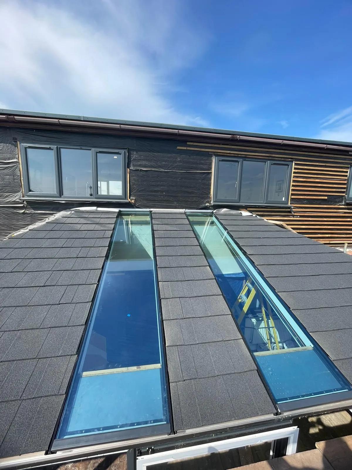 Charcoal tiled roof with two glazed roof panels on a new living space