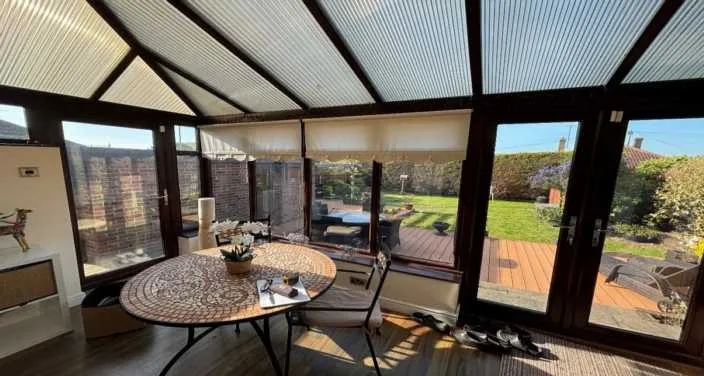 Interior of an old conservatory with a polycarbonate roof and blinds before conversion