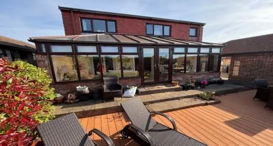 Old brown-framed conservatory at the rear of a house in Caister-on-Sea before replacement