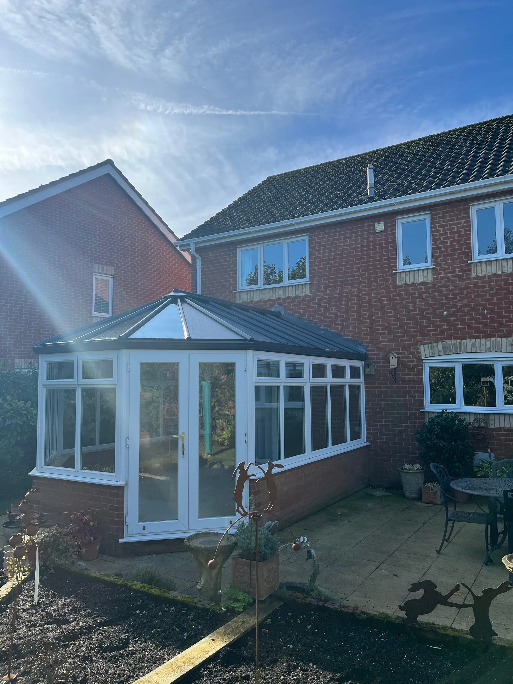 After: glass conservatory roof with aluminium support panels and white uPVC French doors on a red-brick home, Dereham NR20