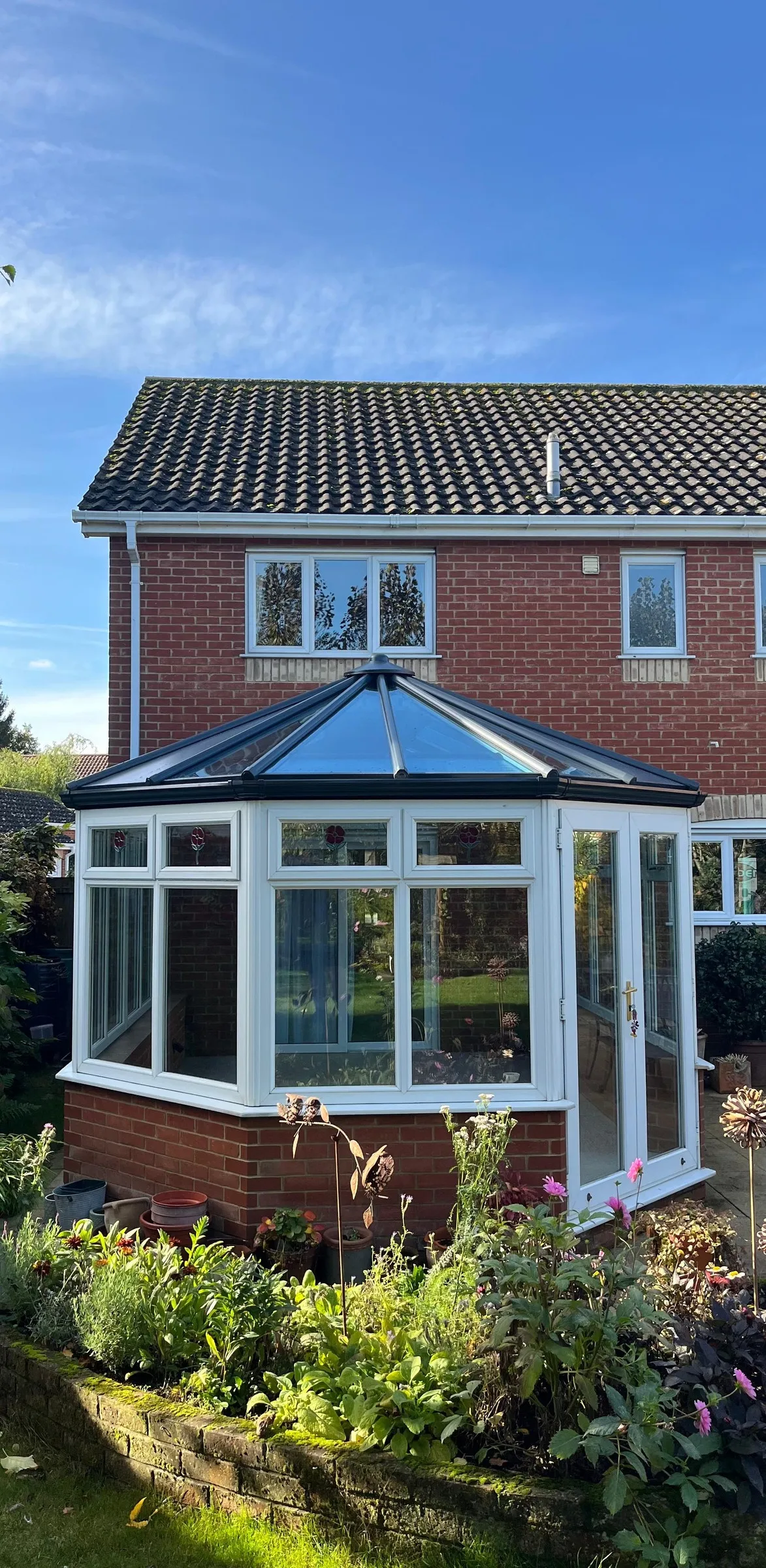 Glass roof Victorian conservatory seen from the garden of a red-brick home in Dereham