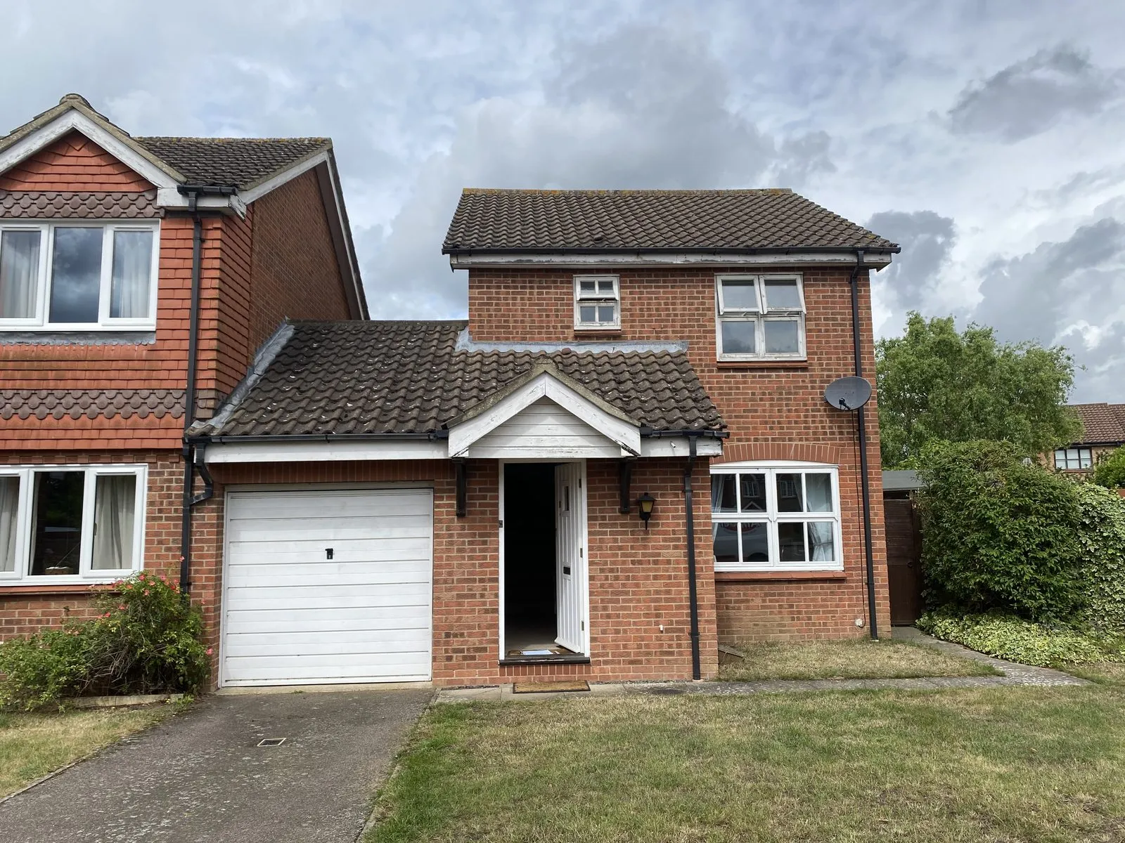 Front of a brick house with a porch in Drayton NR8 before replacement, with white Georgian-bar windows, an old white front door and weathered fascias