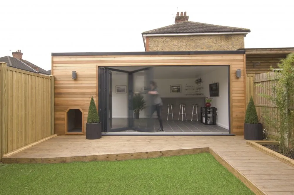 Garage conversion with timber cladding and black bifold doors opening to a decked garden, Drayton NR8