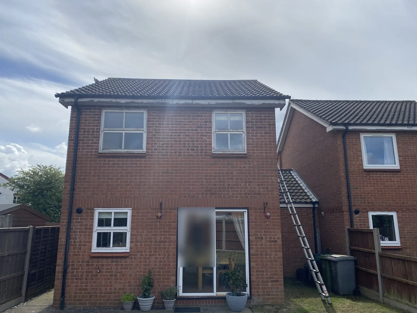 Rear of a brick house in Drayton NR8 before replacement, with old timber windows with glazing bars, weathered fascias and an old sliding patio door