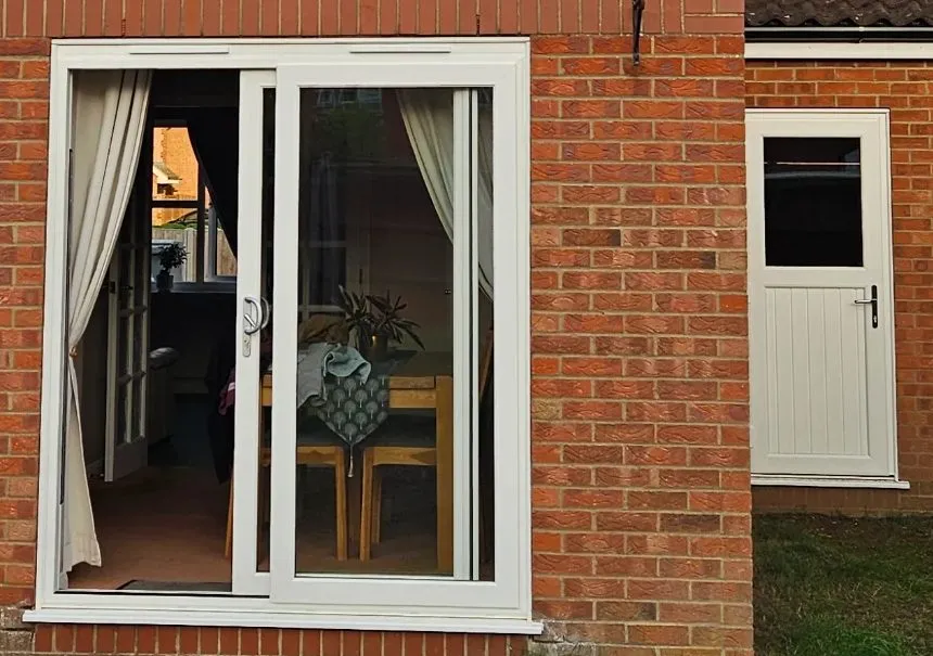 White uPVC sliding patio door and white woodgrain uPVC back door at the rear of a brick house in Drayton NR8