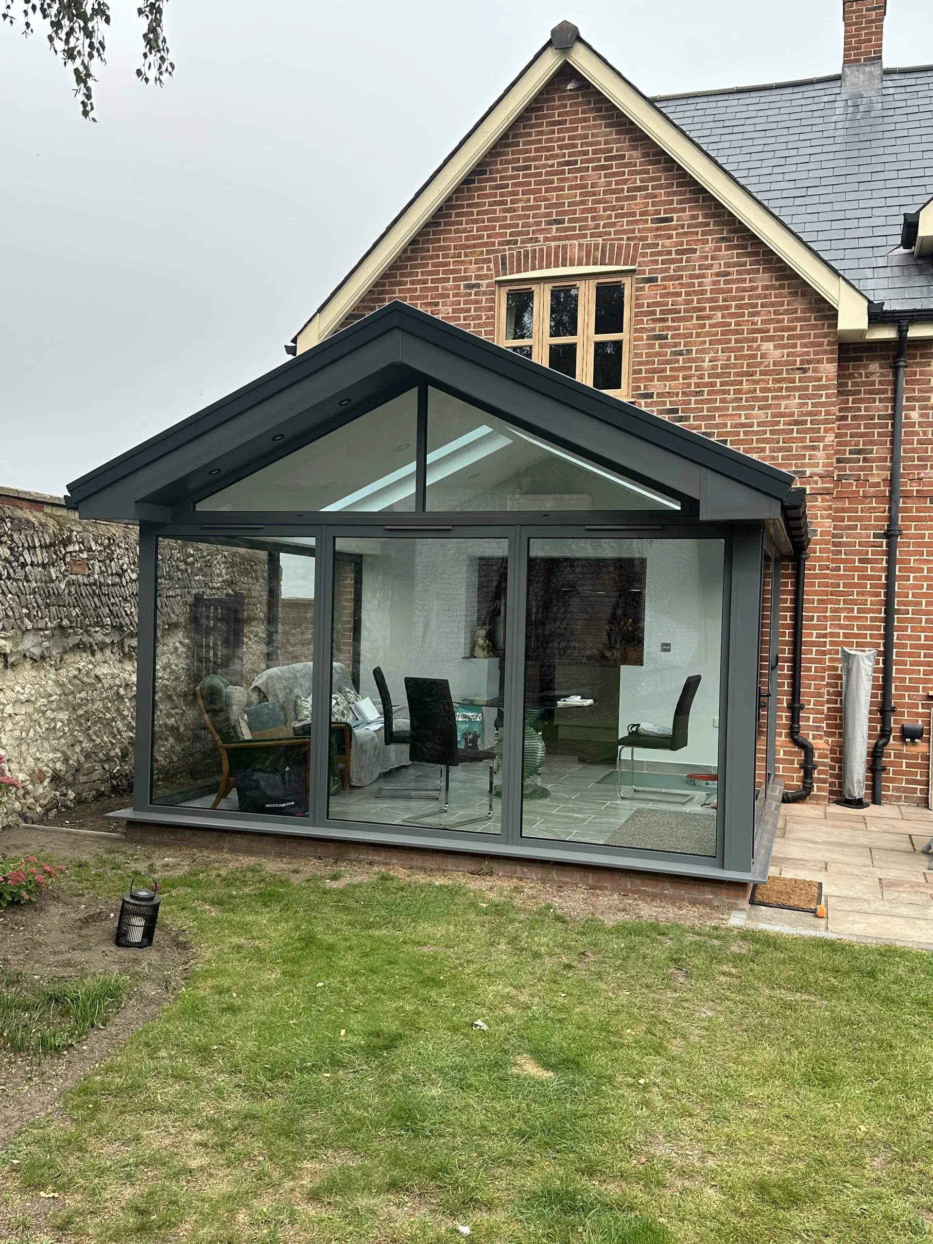 Front view of completed anthracite-framed orangery with glazed gable and Guardian Warm Roof, installed in NR13 by Amber Home Improvements.