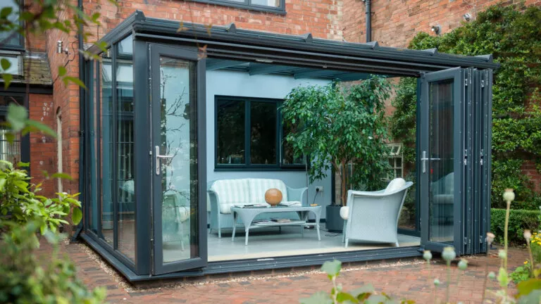 Grey lean-to conservatory with folding doors open to the garden