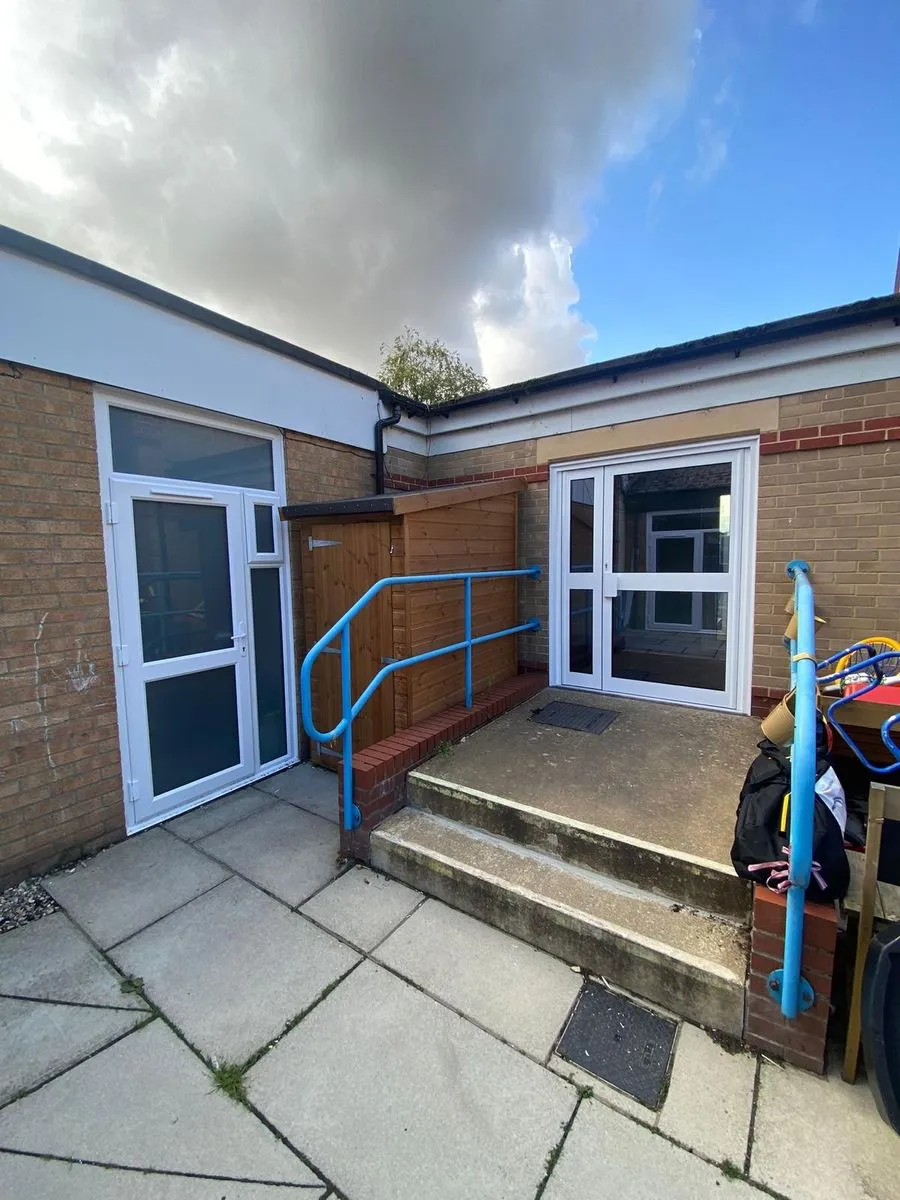 New white aluminium French doors with panic bar beside a white door with side panel at Horsford CofE VA Primary School