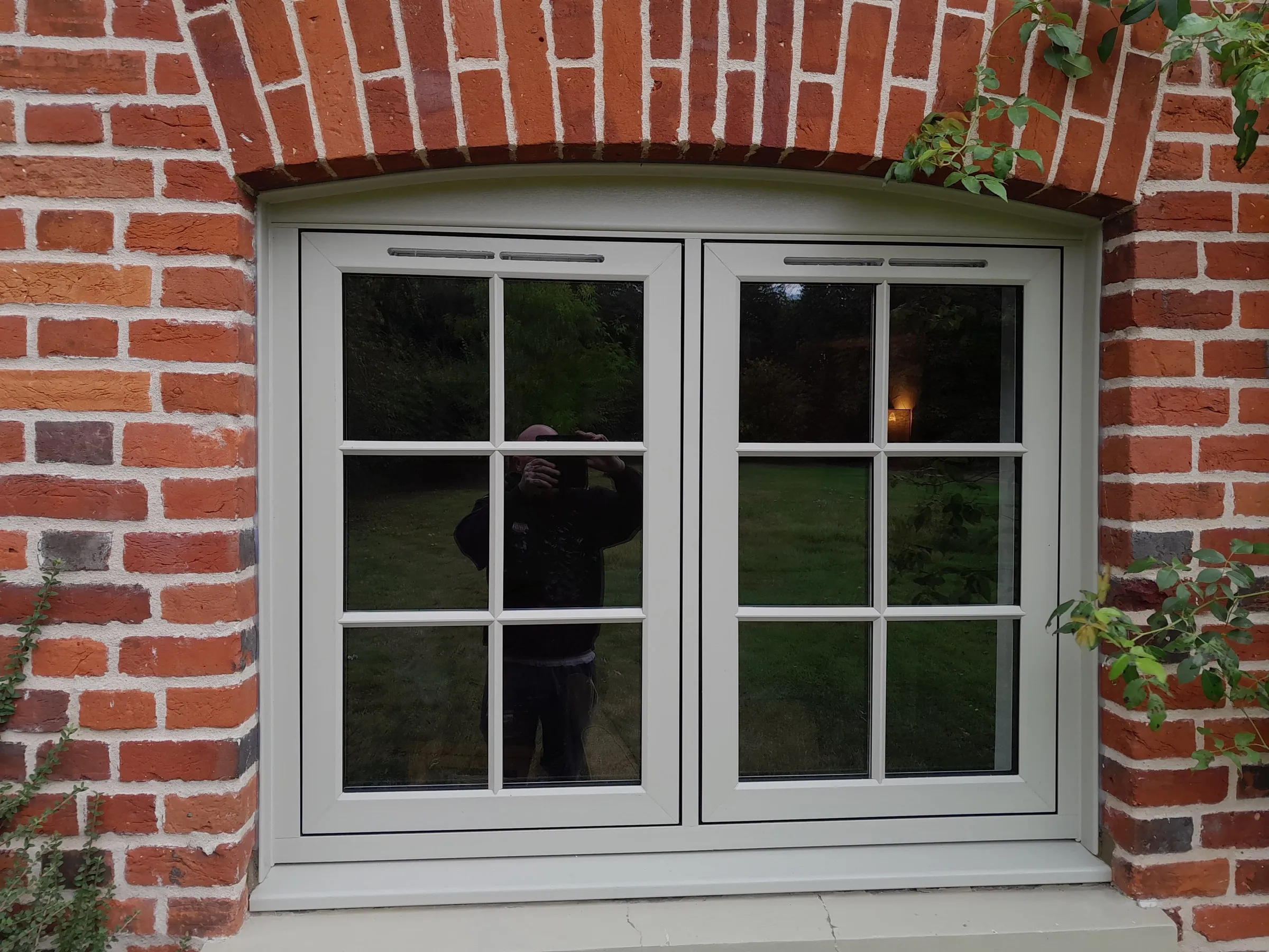Close-up of olive-grey flush casement windows with Georgian bars on red brick, Langham IP31