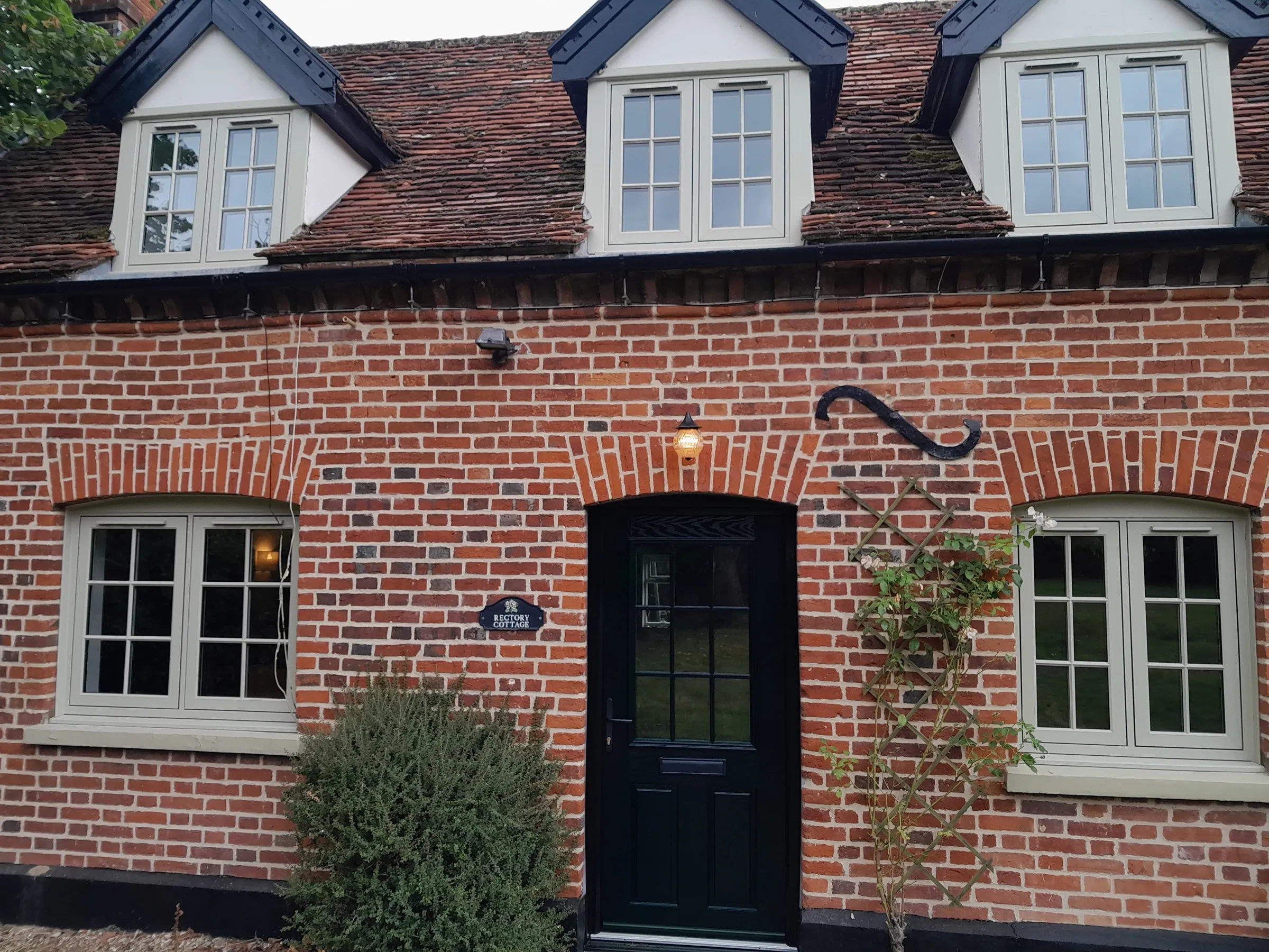 Olive grey flush casement windows with Georgian bars and a black composite front door on a period cottage in Langham IP31