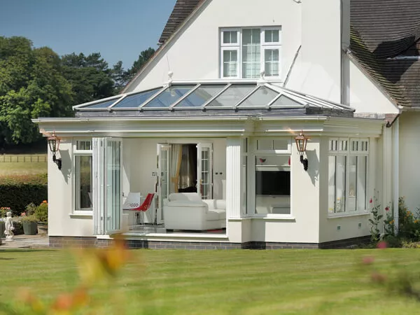Cream orangery with a roof lantern and bi-fold doors opening onto a lawn