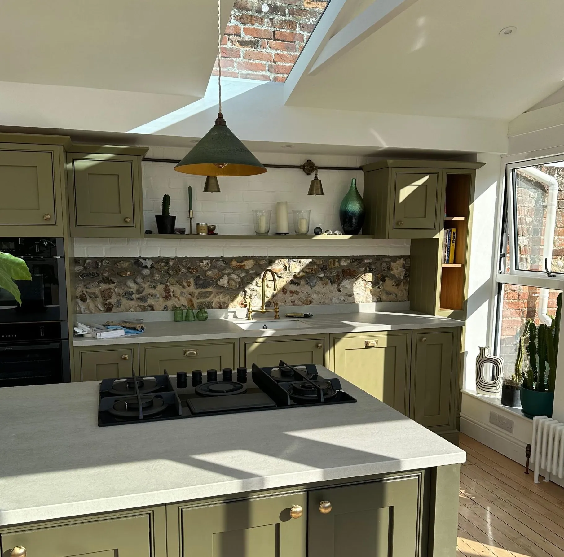 Completed kitchen extension in Loddon, Norfolk with olive green cabinetry, skylight roof windows, and exposed brick feature wall as part of orangery replacement