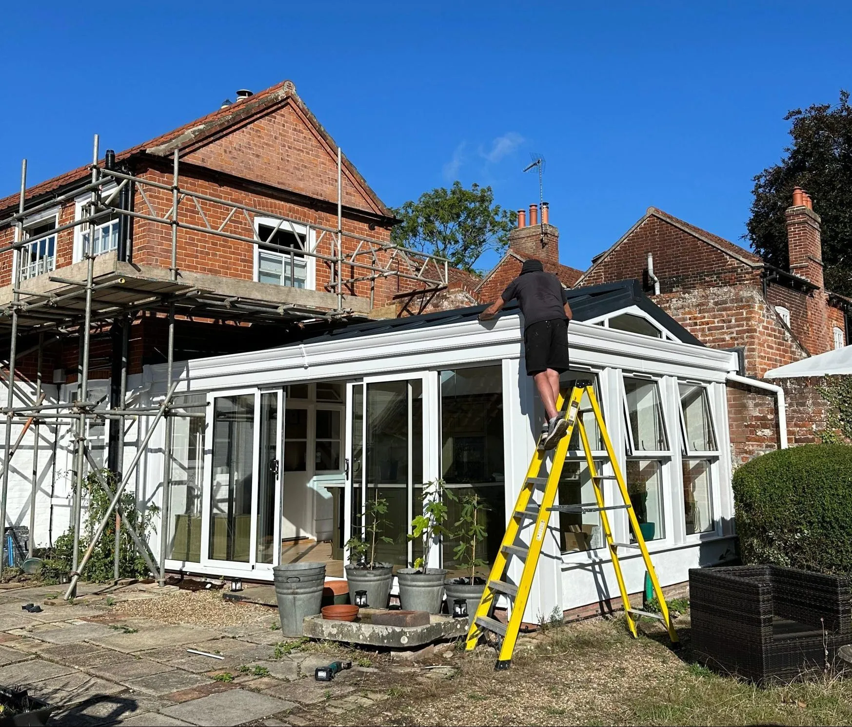 Exterior view of orangery replacement in Loddon, Norfolk during finishing stages, with aluminium frames and new insulated roof installation in progress