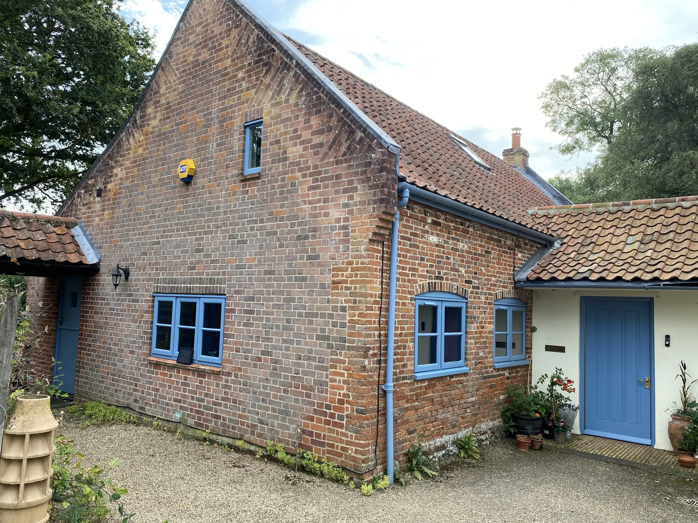 Painted light-blue timber flush casement windows on the red-brick wing at The Old Hall, Mulbarton NR14, before aluminium flush replacement