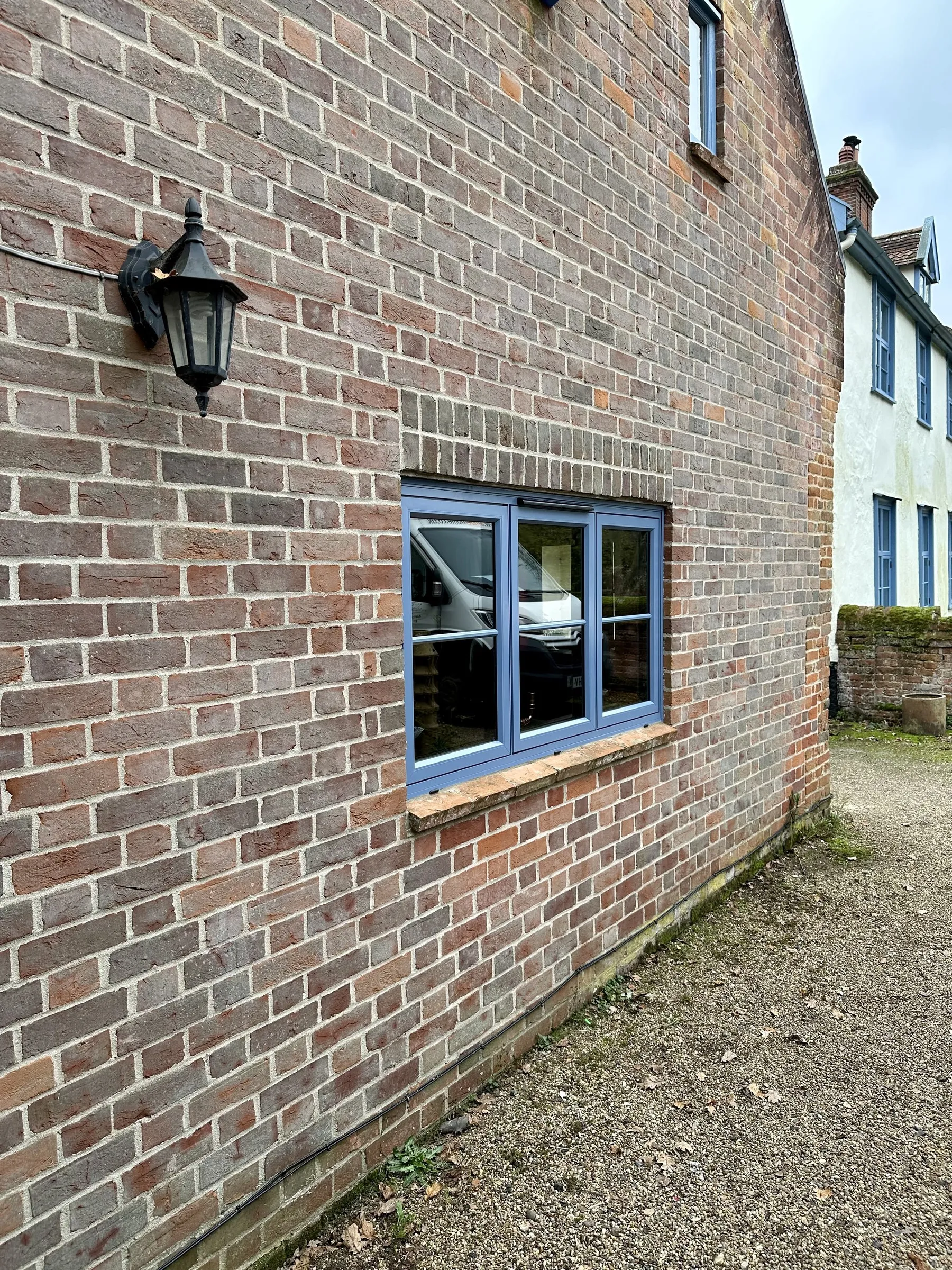 Three-pane aluminium flush casement in duck egg blue on red brick at The Old Hall, Mulbarton NR14