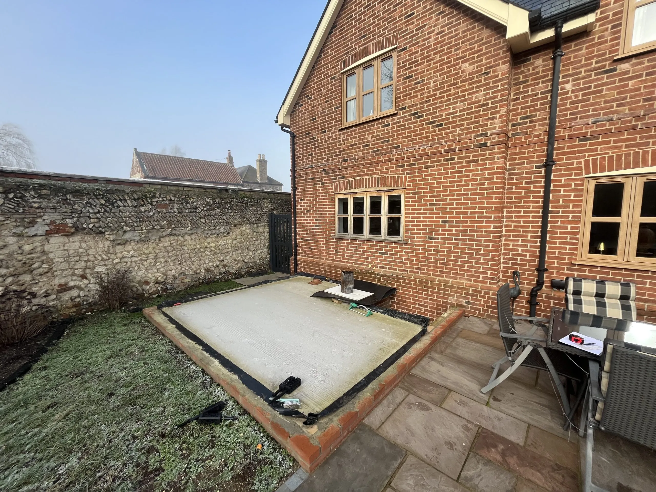 Groundwork stage for new orangery installation in rural Norfolk NR13, showing base slab laid against traditional red brick home.