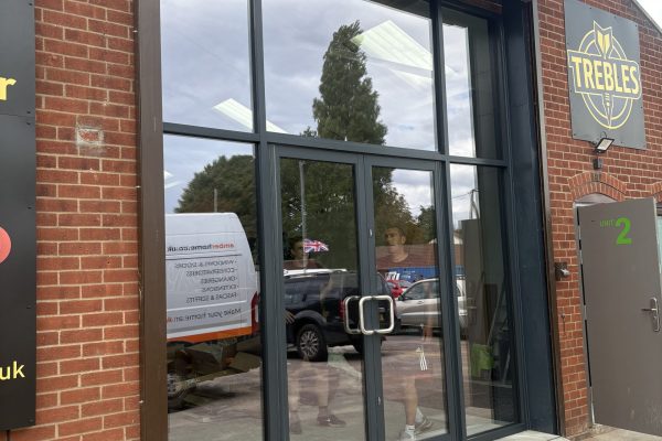 New aluminium shopfront with glazed double doors at Trebles Darts, North Walsham by Amber Home Improvements.