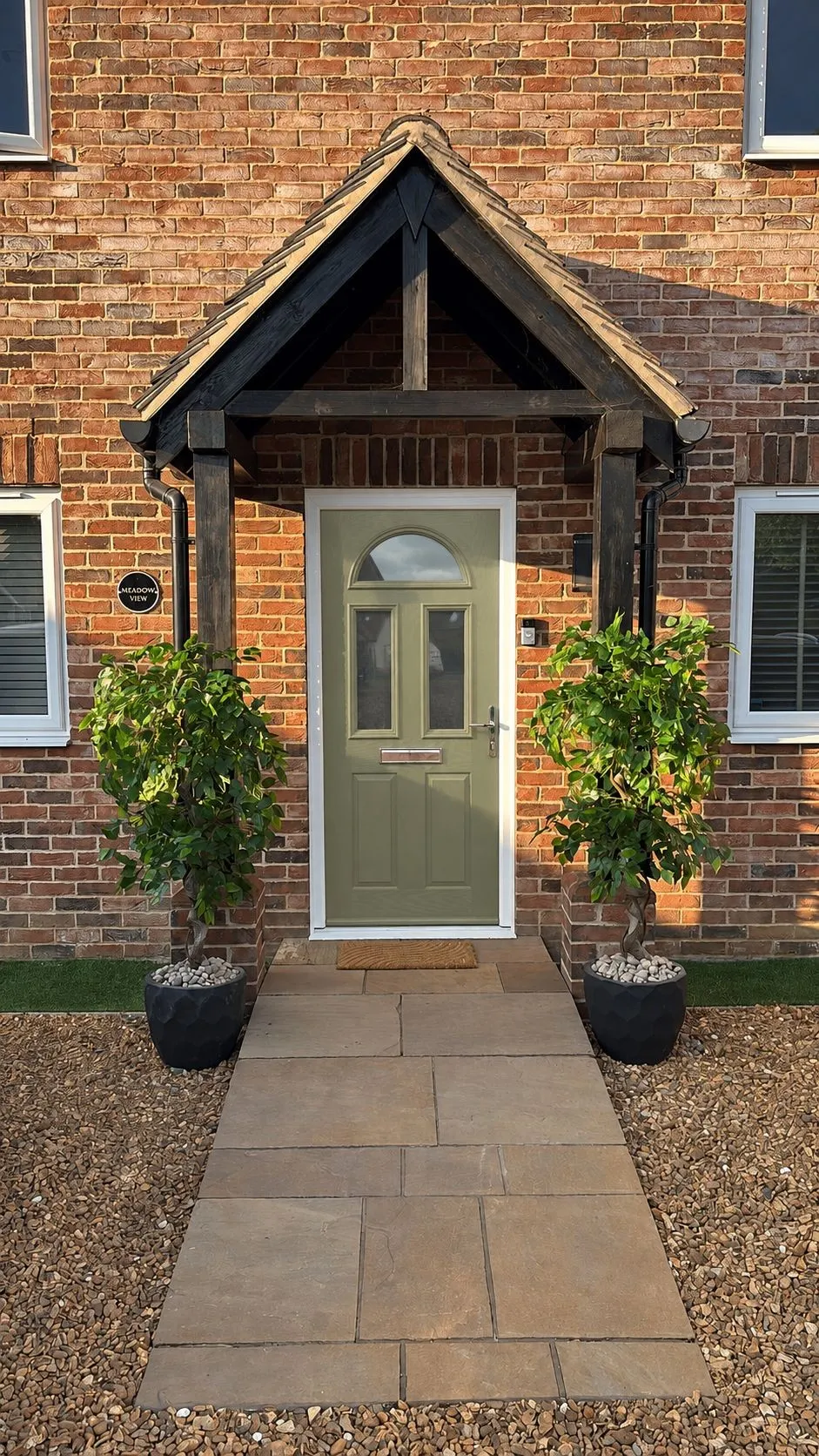Sage-green composite front door with arched top glazing under a timber porch, Shropham NR17