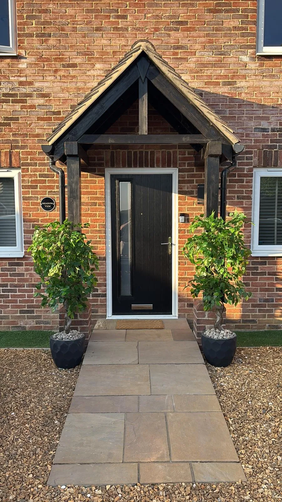 Black composite front door with vertical glazed strip under a timber porch before replacement, Shropham NR17