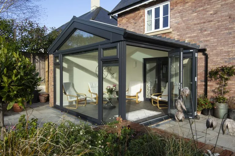 Anthracite grey gable-fronted conservatory with a glazed apex and folding doors