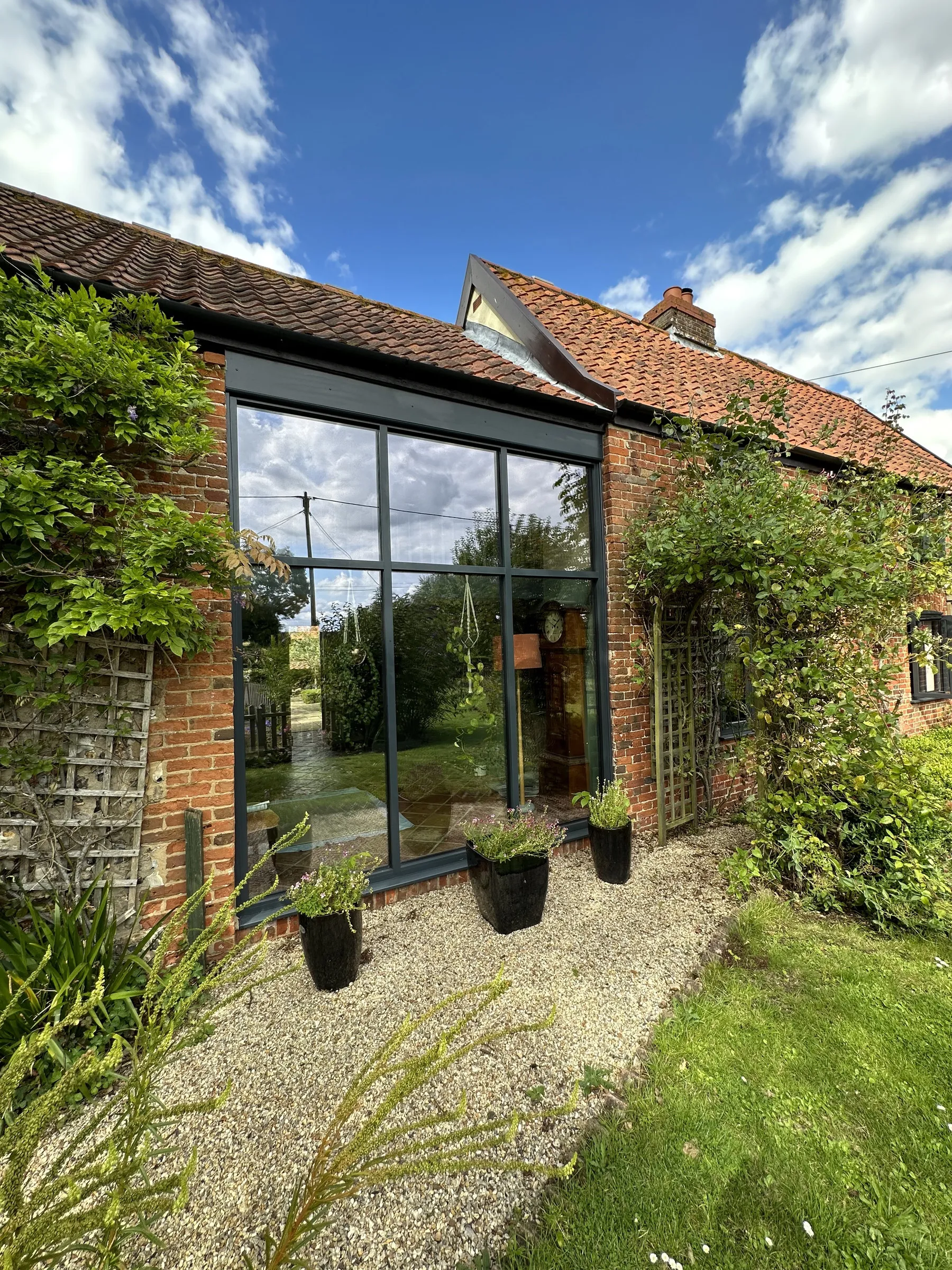 Aluminium SmartWall curtain walling in Anthracite Grey Matt on a red-brick home in Welborne NR20, three upper lights over three tall lower lights