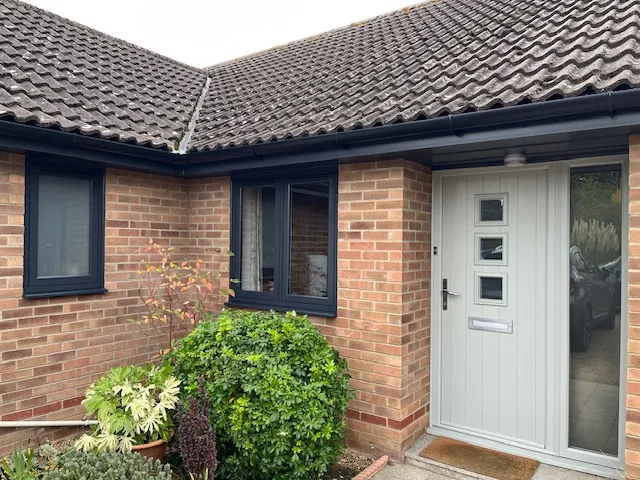 Anthracite flush casement windows and an olive-grey composite front door installed by Amber Home Improvements on a brick bungalow in Wymondham, Norfolk