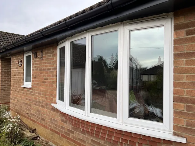 A white uPVC bow window on a brick bungalow in Wymondham, Norfolk, before replacement by Amber Home Improvements.