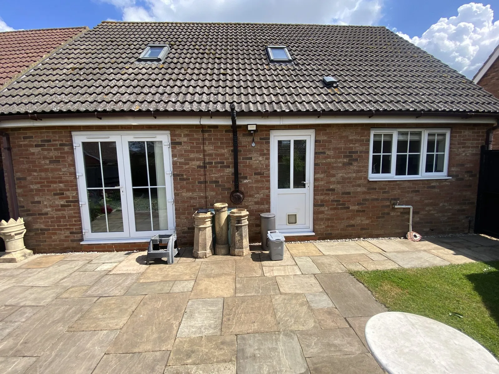Rear of a brick bungalow-style home in the Downham Market area before replacement, with white uPVC windows and doors